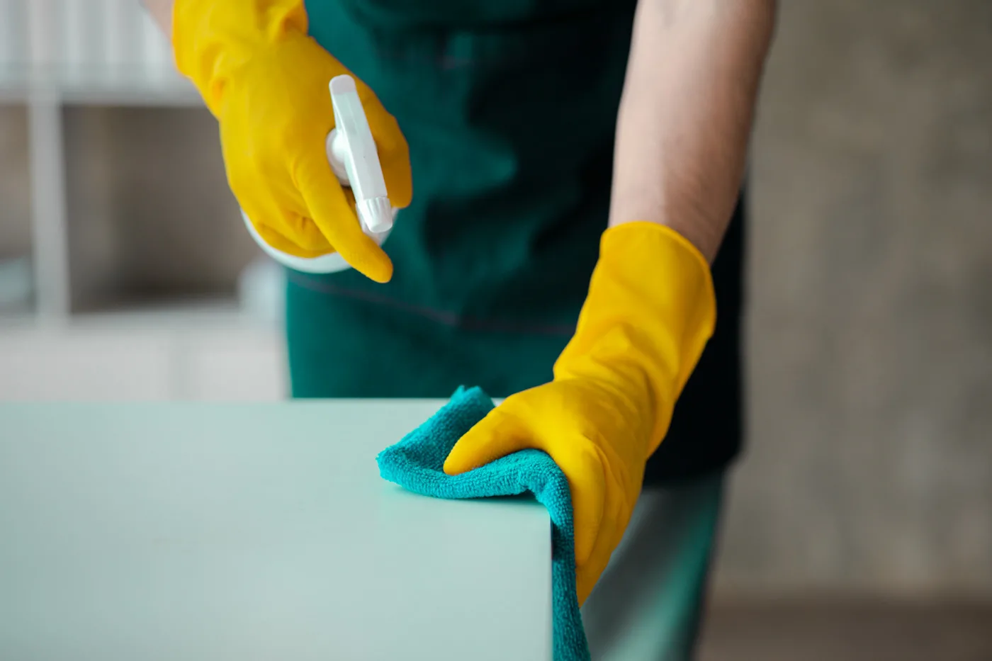 Person cleaning the room, cleaning staff is using cloth and spra