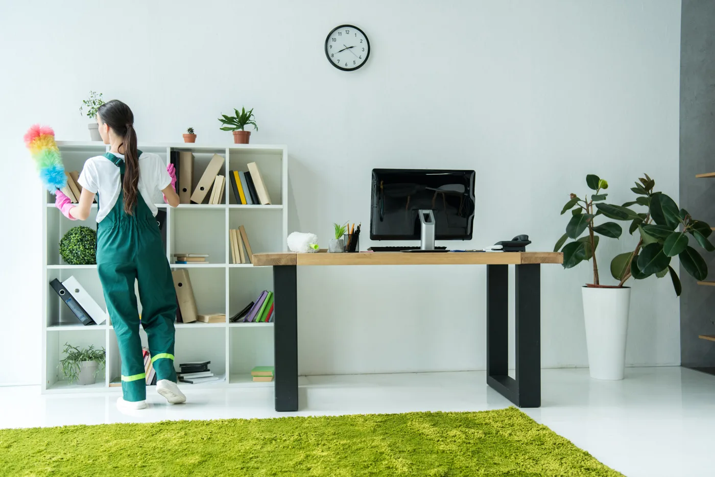 back view of young cleaner holding duster and cleaning modern of