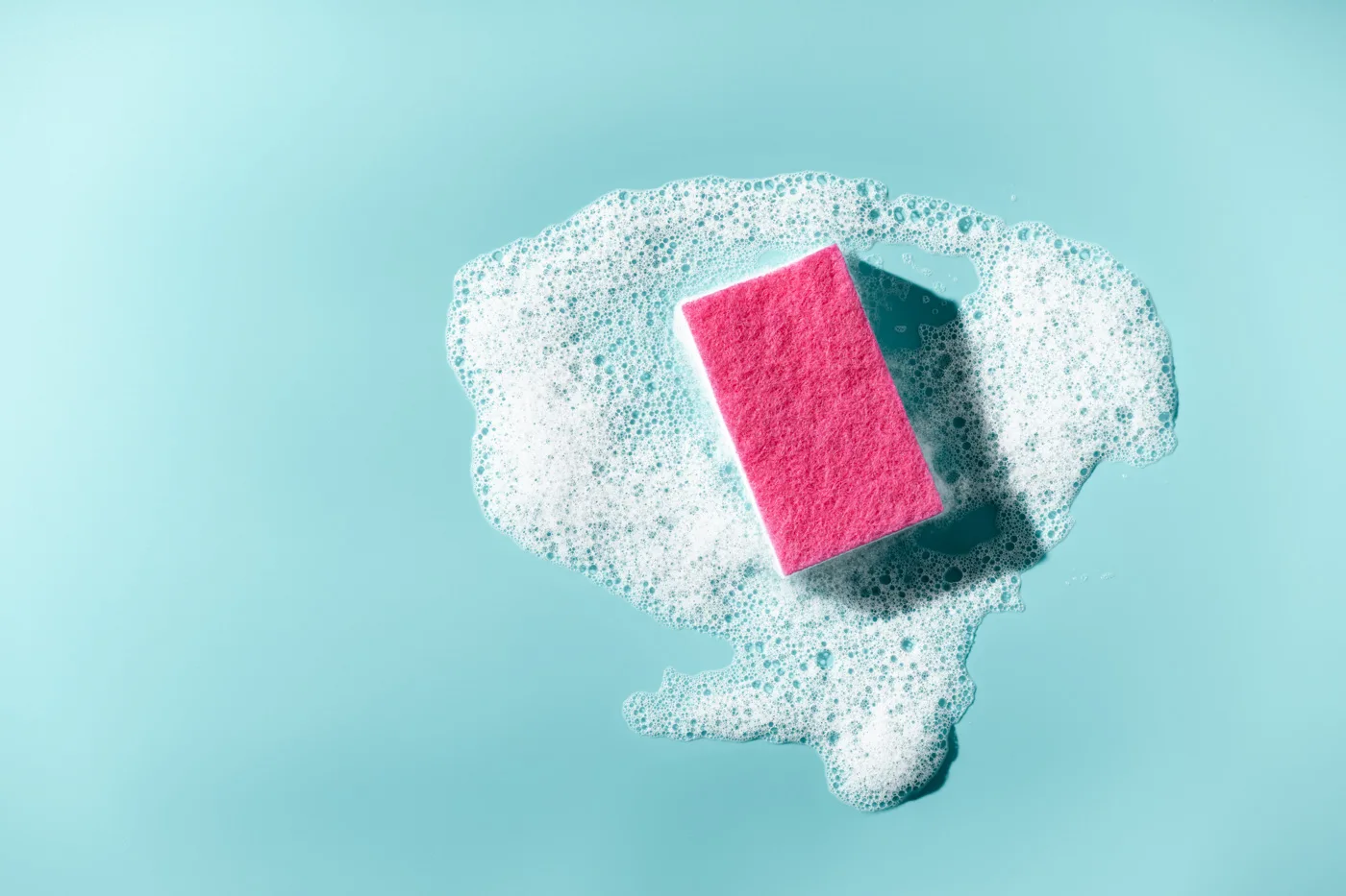 Cleaning sponge and a soapy foam on a blue background. Cleaning
